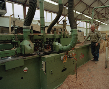822290 Afbeelding van een werknemer bezig aan een zaagmachine in de werkplaats van Aannemingsbedrijf H.J. Jurriëns ...